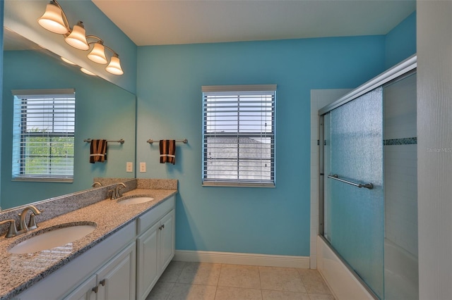 full bath with baseboards, double vanity, tile patterned flooring, and enclosed tub / shower combo