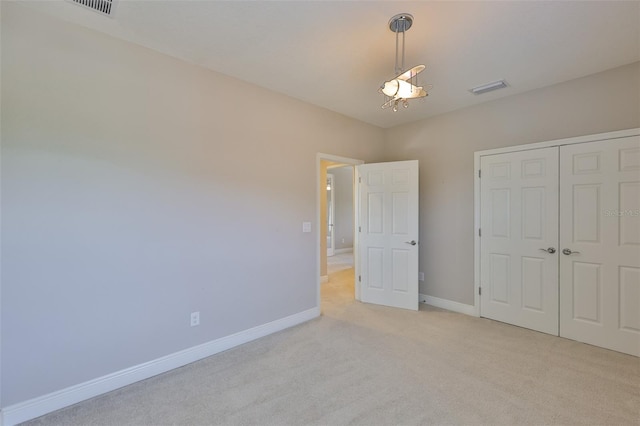 unfurnished bedroom with light carpet, baseboards, and a closet