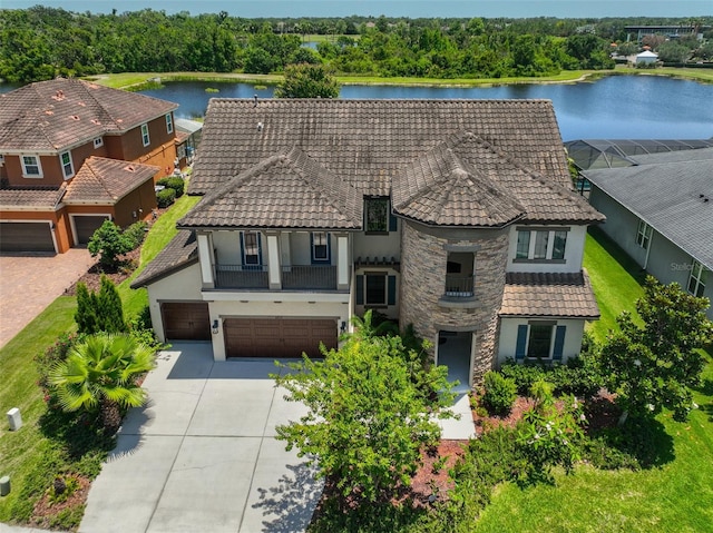 view of front of house featuring stucco siding, a tile roof, concrete driveway, a water view, and a garage