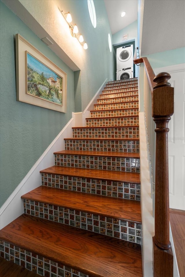 1963 Edgewater Dr, Clearwater, FL 33755 - staircase featuring estacked washer and dryer, vaulted ceiling, and wood finished floors