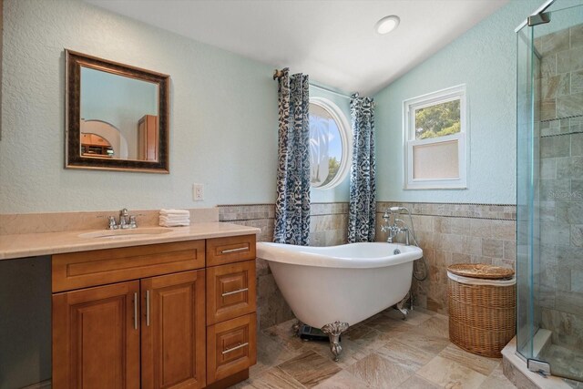 1963 Edgewater Dr, Clearwater, FL 33755 - full bathroom featuring a shower stall, lofted ceiling, vanity, a freestanding bath, and tile walls
