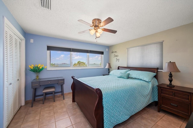 1963 Edgewater Dr, Clearwater, FL 33755 - bedroom featuring a closet, a textured ceiling, light tile patterned flooring, and a ceiling fan