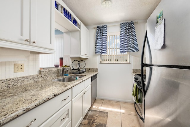 kitchen featuring stainless steel appliances, a sink, backsplash, white cabinets, and a textured ceiling