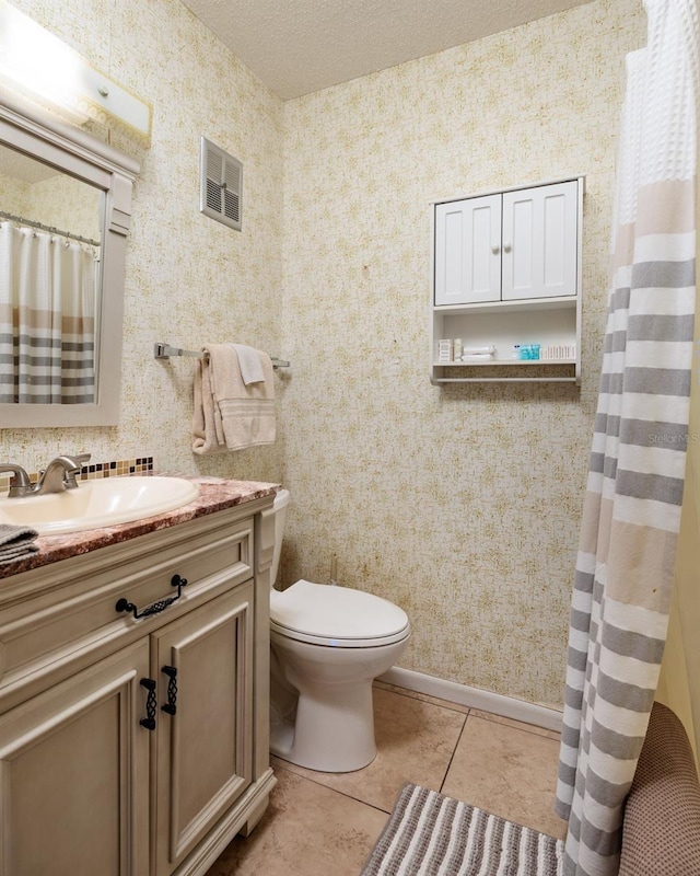bathroom with toilet, vanity, wallpapered walls, tile patterned floors, and a textured ceiling