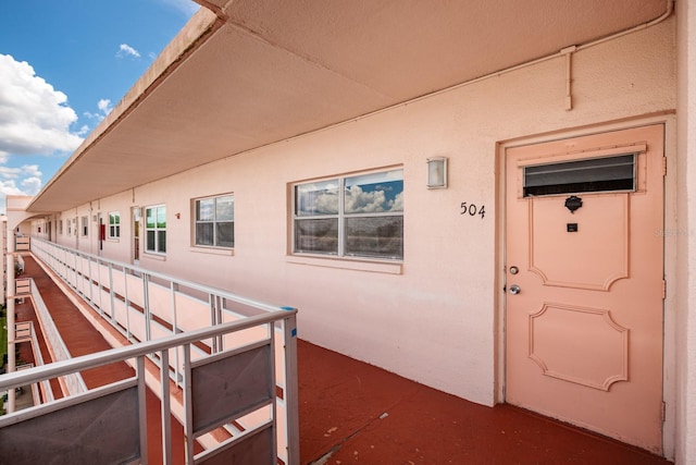 property entrance with a balcony and stucco siding