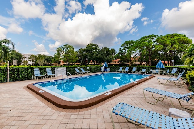 community pool with a patio and fence