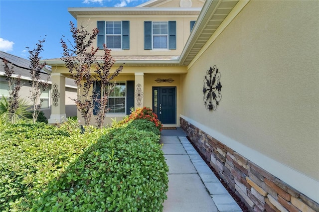 doorway to property featuring stucco siding and covered porch