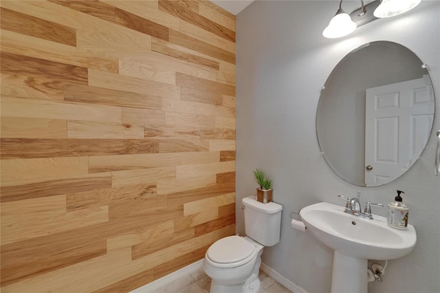 bathroom featuring toilet, a sink, tile patterned floors, and baseboards
