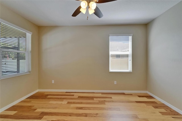 empty room with light wood-type flooring, a ceiling fan, and baseboards