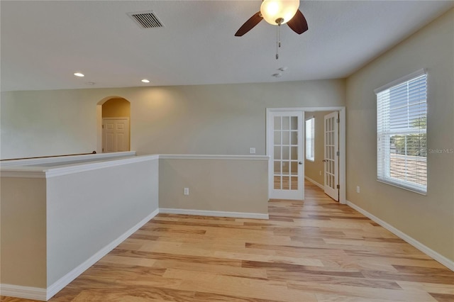 empty room featuring arched walkways, light wood-style floors, recessed lighting, ceiling fan, and baseboards