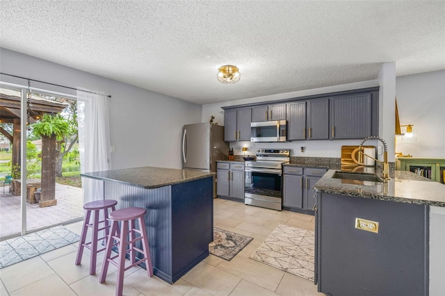 13643 Tramore Dr, Odessa, FL 33556 - kitchen with stainless steel appliances, a sink, a kitchen bar, a kitchen island, and a textured ceiling