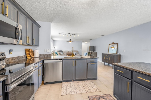 13643 Tramore Dr, Odessa, FL 33556 - kitchen featuring stainless steel appliances, a peninsula, a ceiling fan, open floor plan, and a textured ceiling