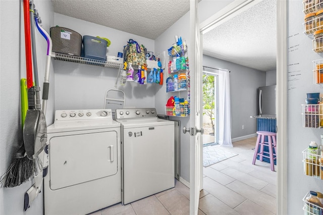13643 Tramore Dr, Odessa, FL 33556 - clothes washing area with washer and clothes dryer, a textured ceiling, light tile patterned floors, and baseboards