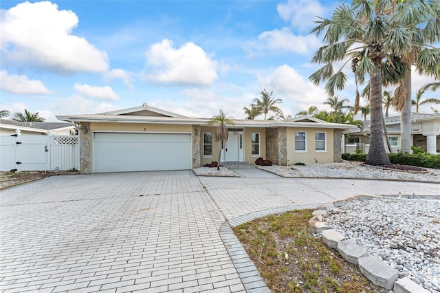 5 Marina Ter, Treasure Island, FL 33706 - ranch-style home featuring stone siding, a gate, decorative driveway, and an attached garage