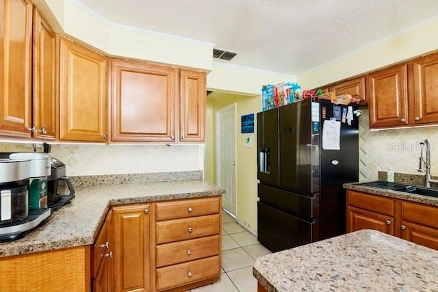 9802 N Oregon Ave, Tampa, FL 33612 - kitchen with black fridge, tasteful backsplash, a sink, light tile patterned floors, and brown cabinetry