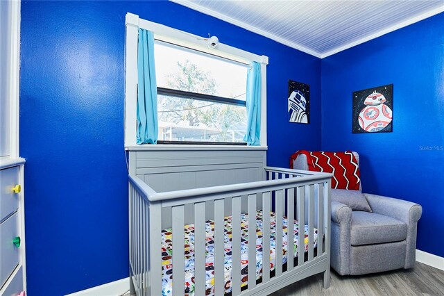 9802 N Oregon Ave, Tampa, FL 33612 - bedroom with a nursery area, baseboards, wood finished floors, and ornamental molding