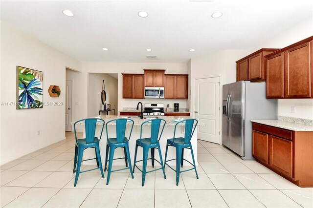 5247 Wildwood Way, Davenport, FL 33837 - kitchen with stainless steel appliances, recessed lighting, brown cabinetry, a kitchen bar, and an island with sink