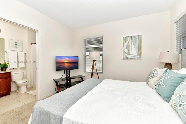 5247 Wildwood Way, Davenport, FL 33837 - bedroom featuring light tile patterned flooring, light colored carpet, connected bathroom, and baseboards