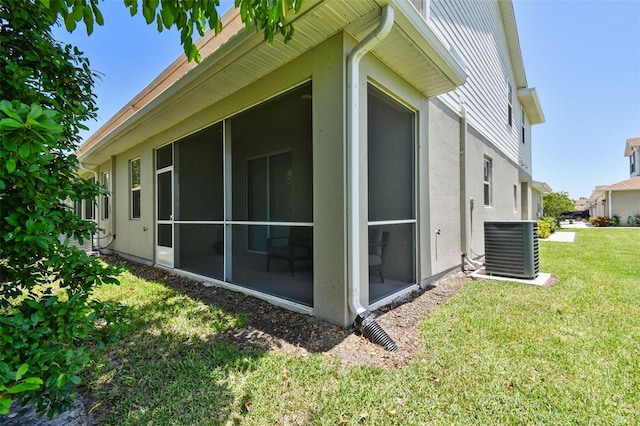 5270 Neil Dr, Saint Petersburg, FL 33714 - view of side of property with a sunroom, central AC, a lawn, and stucco siding