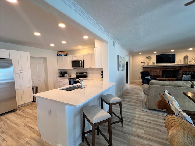 474 20th Ave, Indian Rocks Beach, FL 33785 - kitchen with stainless steel appliances, a breakfast bar area, white cabinets, a brick fireplace, and a peninsula