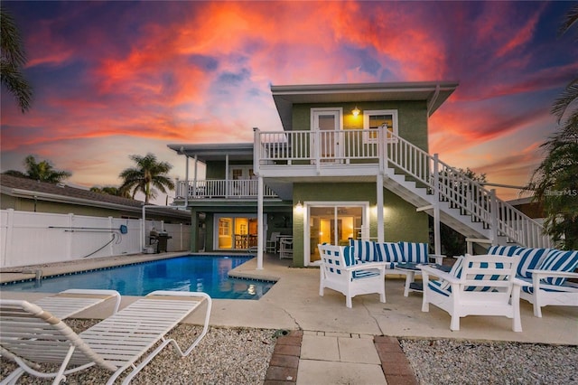 474 20th Ave, Indian Rocks Beach, FL 33785 - back of property at dusk featuring stairs, a balcony, a fenced backyard, and stucco siding