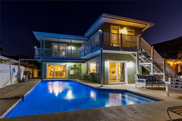 474 20th Ave, Indian Rocks Beach, FL 33785 - back of house at twilight featuring a balcony, a patio, stairway, and stucco siding