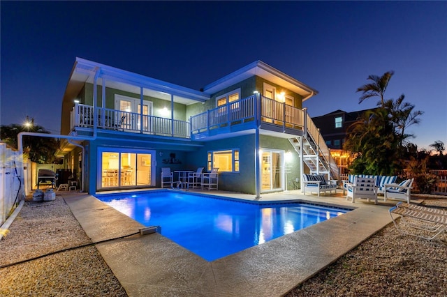 474 20th Ave, Indian Rocks Beach, FL 33785 - back of house at night with a balcony, a patio area, an outdoor living space, and an outdoor pool
