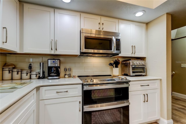 9484 Tara Cay Ct Unit 8, Seminole, FL 33776 - kitchen with stainless steel appliances, light countertops, white cabinetry, backsplash, and recessed lighting