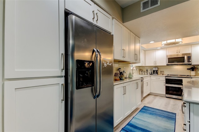 9484 Tara Cay Ct Unit 8, Seminole, FL 33776 - kitchen with stainless steel appliances, decorative backsplash, white cabinetry, and light countertops