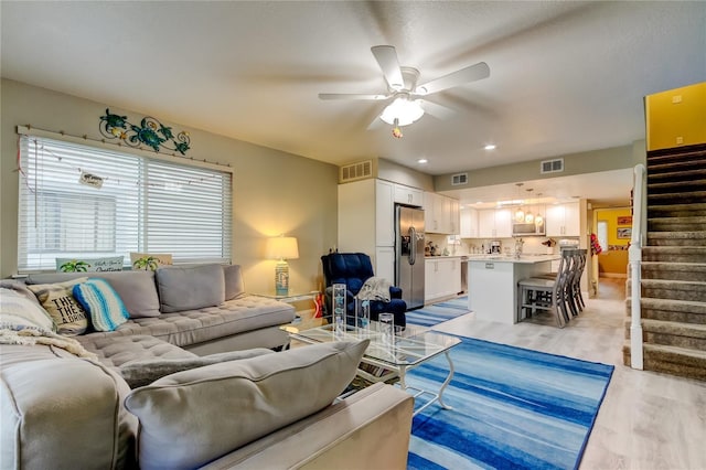 9484 Tara Cay Ct Unit 8, Seminole, FL 33776 - living room featuring ceiling fan, light wood finished floors, and stairway