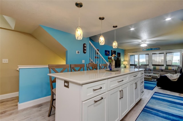 9484 Tara Cay Ct Unit 8, Seminole, FL 33776 - kitchen featuring a kitchen bar, a ceiling fan, open floor plan, white cabinets, and light wood-type flooring