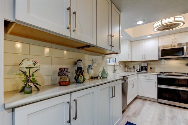 9484 Tara Cay Ct Unit 8, Seminole, FL 33776 - kitchen featuring appliances with stainless steel finishes, a sink, light countertops, white cabinetry, and decorative backsplash