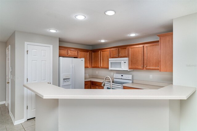 6954 Hawthorne Trace Ln, Riverview, FL 33578 - kitchen with white appliances, light countertops, brown cabinetry, a peninsula, and light tile patterned floors