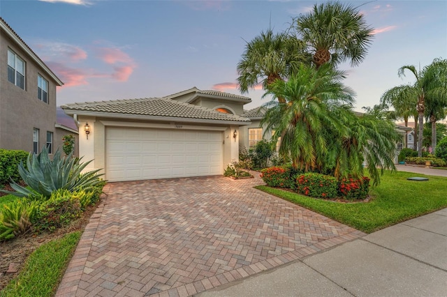 5009 Sandy Brook Cir, Wimauma, FL 33598 - mediterranean / spanish-style house featuring decorative driveway, stucco siding, a garage, and a tiled roof