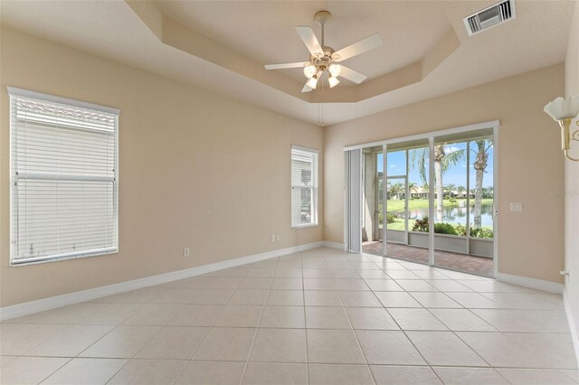 5009 Sandy Brook Cir, Wimauma, FL 33598 - spare room with a ceiling fan, a tray ceiling, light tile patterned floors, and a water view