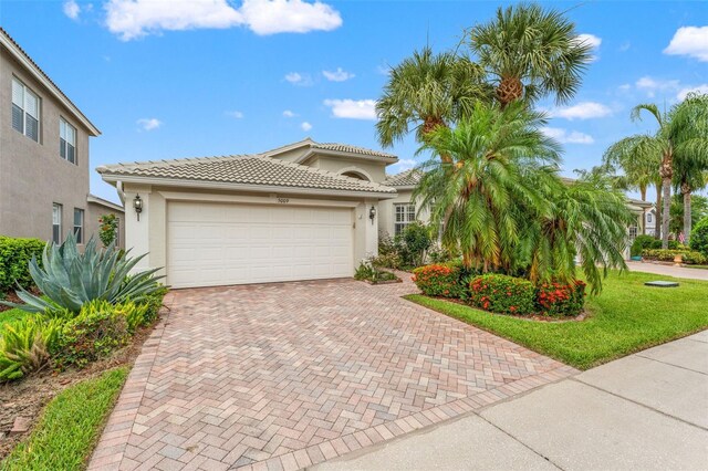 5009 Sandy Brook Cir, Wimauma, FL 33598 - mediterranean / spanish home with decorative driveway, stucco siding, an attached garage, and a tiled roof