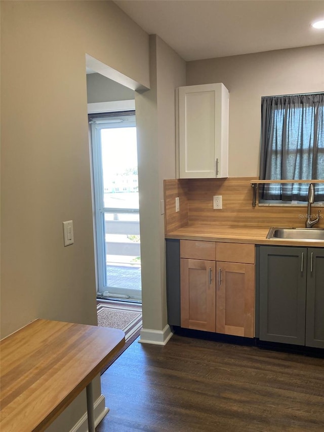 kitchen featuring a sink, dark wood-type flooring, light countertops, white cabinetry, and tasteful backsplash