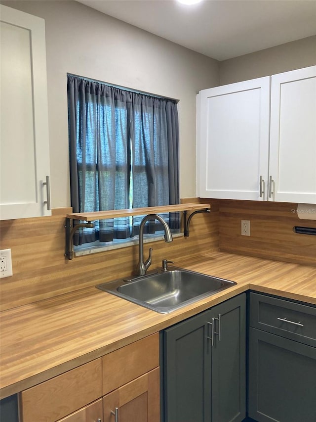kitchen featuring butcher block counters, a sink, and white cabinets
