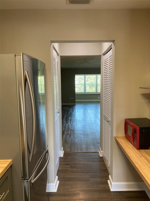 corridor with dark wood finished floors and baseboards