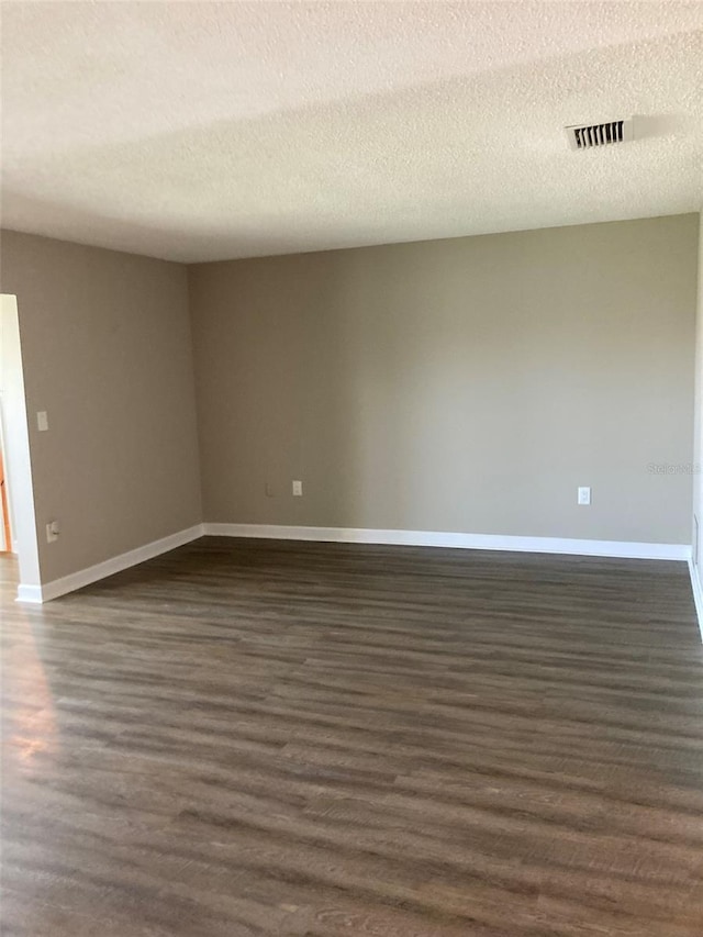 empty room with baseboards, dark wood-type flooring, and a textured ceiling