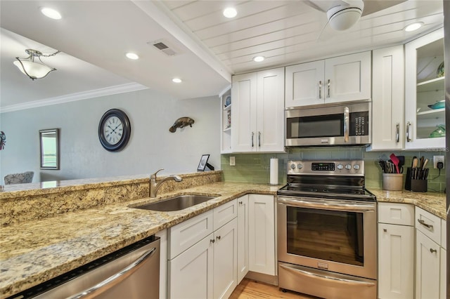 200 1st Ave Unit 309, St Pete Beach, FL 33706 - kitchen with stainless steel appliances, a sink, crown molding, white cabinets, and light stone countertops