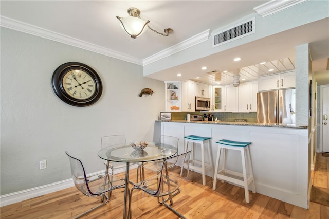 200 1st Ave Unit 309, St Pete Beach, FL 33706 - dining room with crown molding, light wood-style floors, baseboards, and recessed lighting