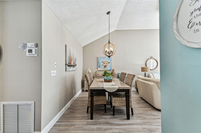 3520 51st Ave W, Bradenton, FL 34210 - dining space featuring light wood-style floors, a textured ceiling, a chandelier, vaulted ceiling, and baseboards