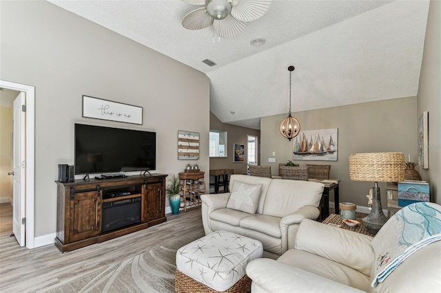 3520 51st Ave W, Bradenton, FL 34210 - living room with light wood finished floors, ceiling fan, a chandelier, vaulted ceiling, and baseboards