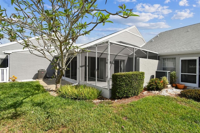 3520 51st Ave W, Bradenton, FL 34210 - back of property featuring a lawn, stucco siding, a lanai, central AC, and a shingled roof