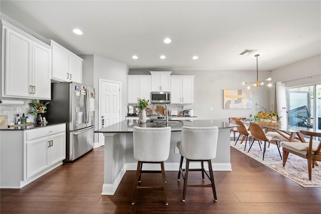 kitchen with stainless steel appliances, decorative backsplash, dark countertops, recessed lighting, and a kitchen island with sink
