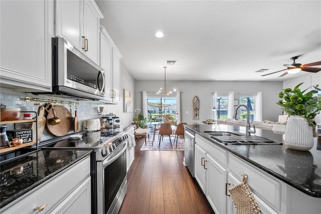 kitchen with appliances with stainless steel finishes, a sink, white cabinetry, tasteful backsplash, and ceiling fan