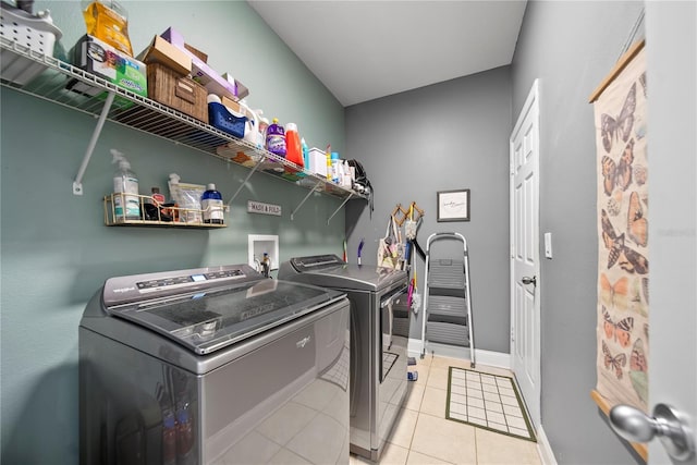 laundry area with separate washer and dryer, light tile patterned floors, and baseboards