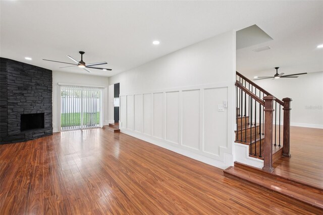226 Willowick Ave, Temple Terrace, FL 33617 - unfurnished living room featuring ceiling fan, a decorative wall, wood finished floors, stairway, and a fireplace
