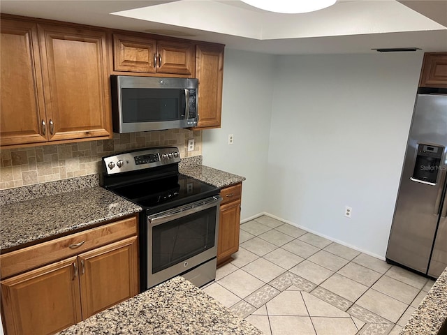 647 Fairmont Ave Unit C, Safety Harbor, FL 34695 - kitchen with appliances with stainless steel finishes, brown cabinetry, dark stone counters, decorative backsplash, and light tile patterned floors